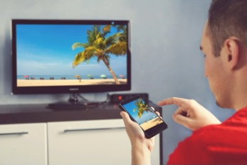 A man using iPhone and looking at Smart TV.