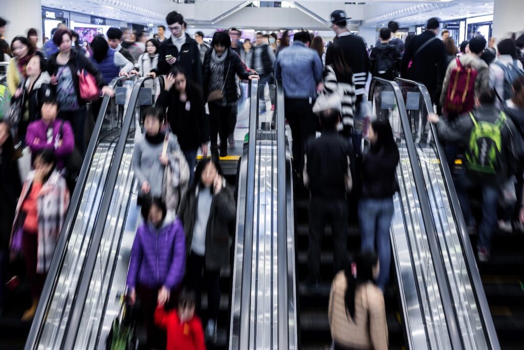 People going up and down an escalator at a shopping mall.
