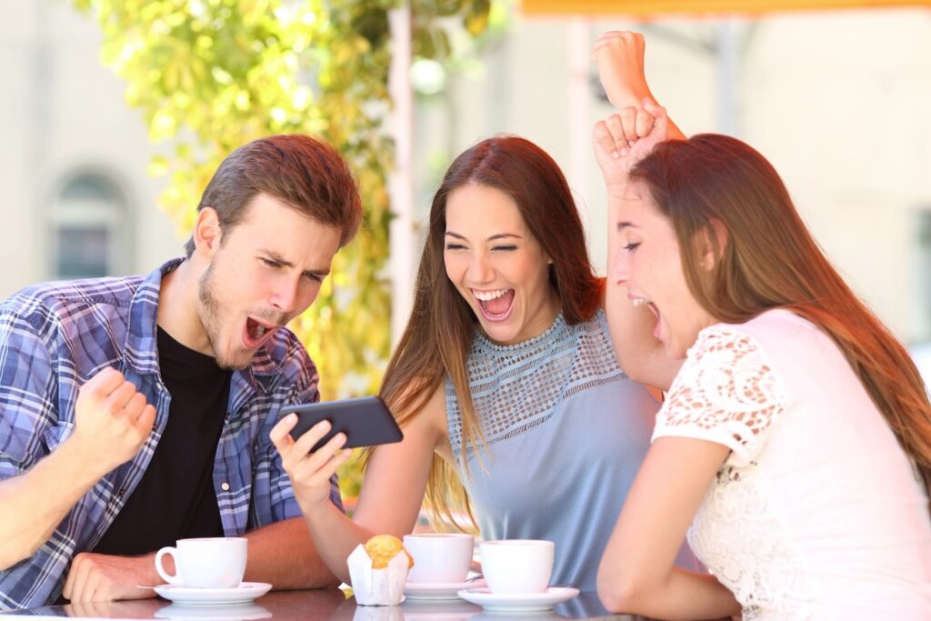 Three excited friends watching sports on a smart phone.