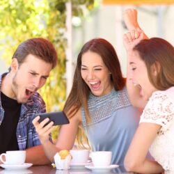 Three excited friends watching sports on a smart phone.