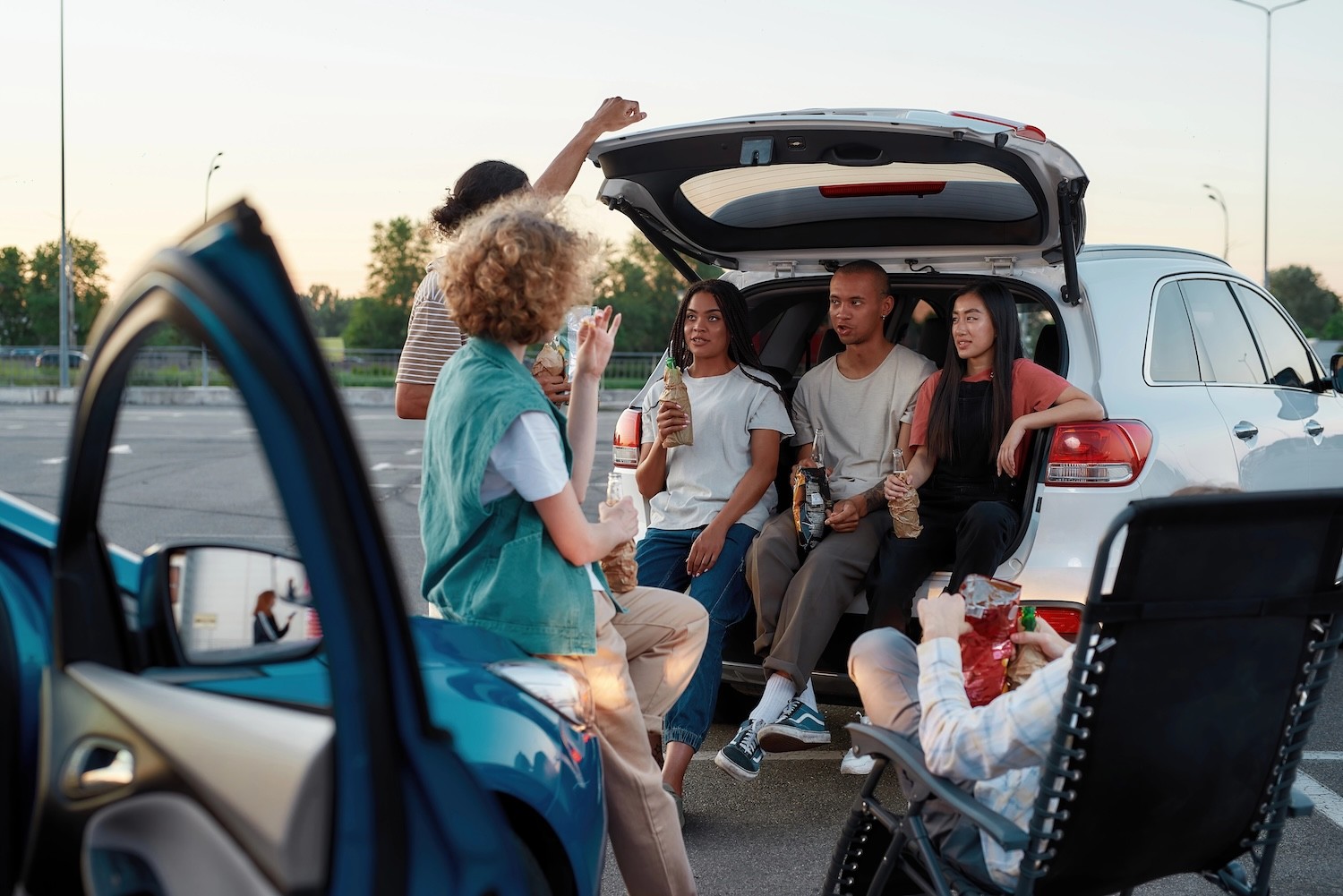 A group of young adults tailgating in a parking lot. 