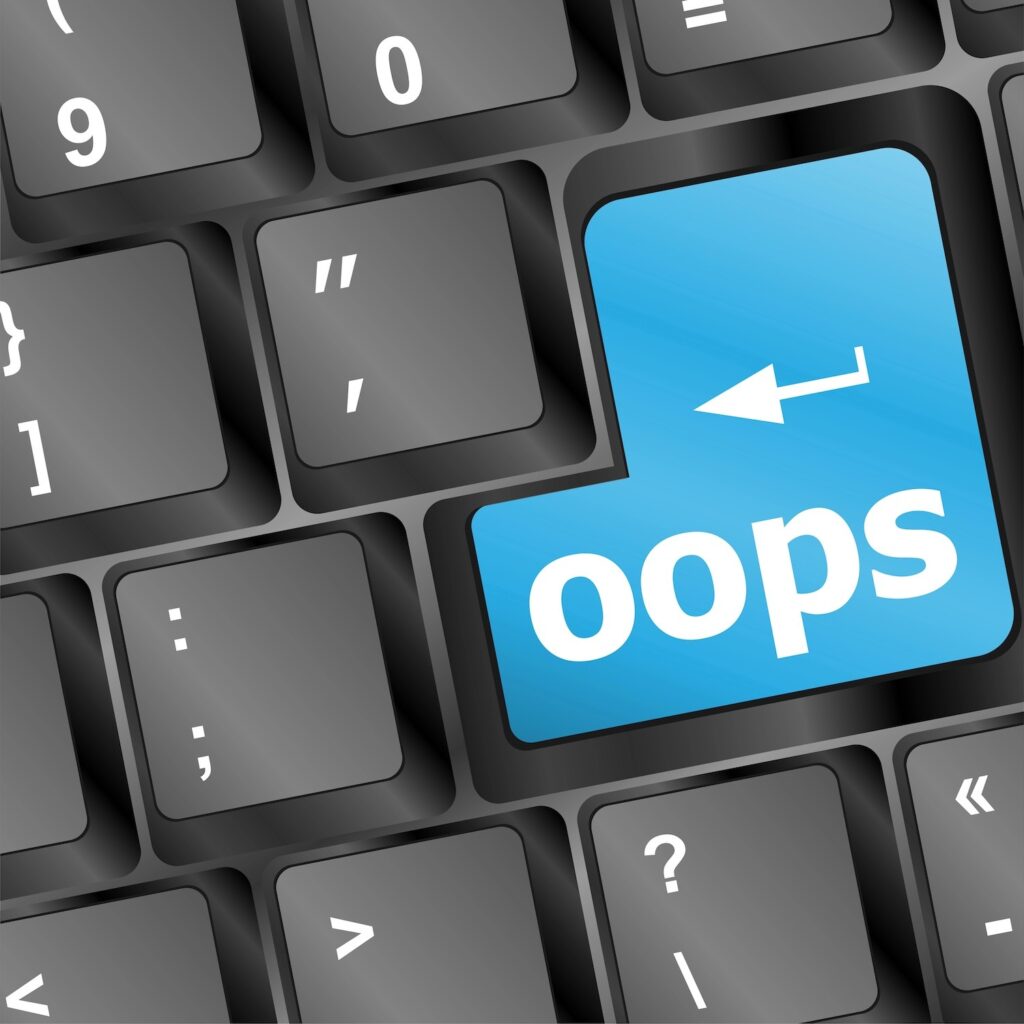 Photo of a keyboard with a large blue button reading "oops".