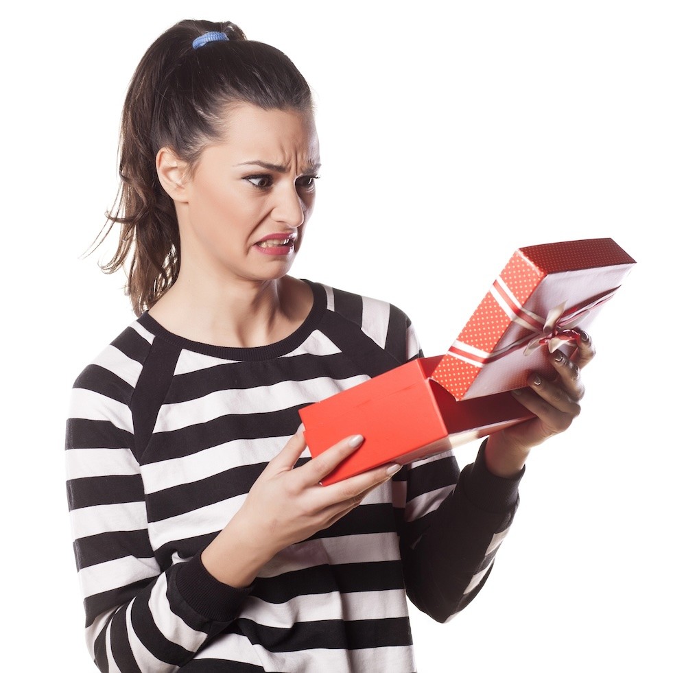 Disappointed woman holding a gift in her hands.