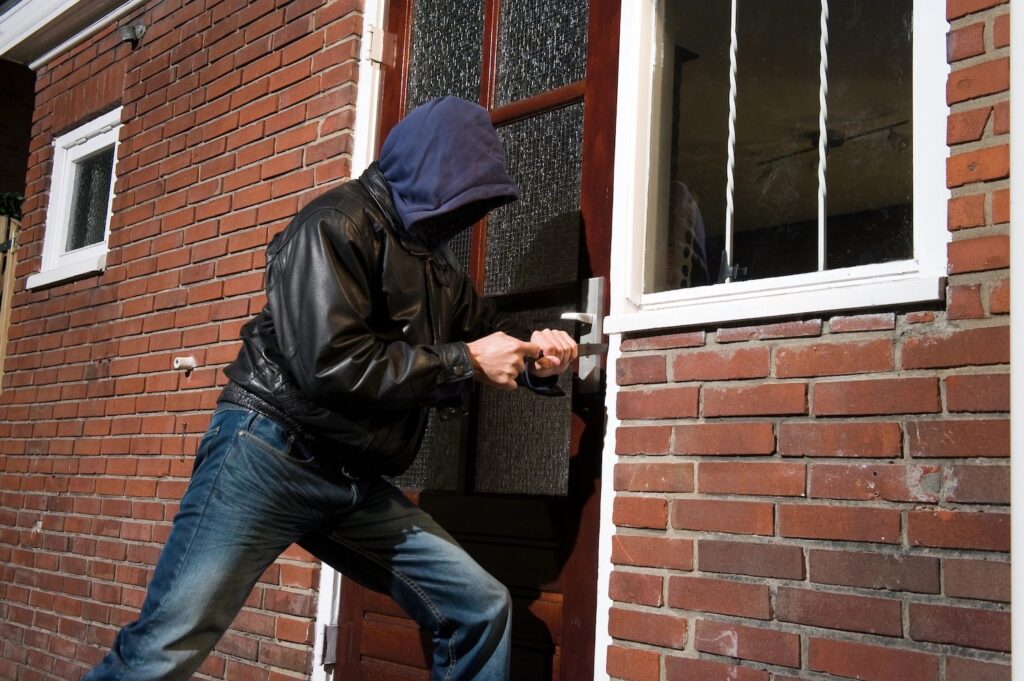 A burglar trying to get in a house through the back door.