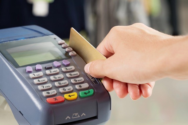 Close up of a payment machine with a hand nearby with credit card.