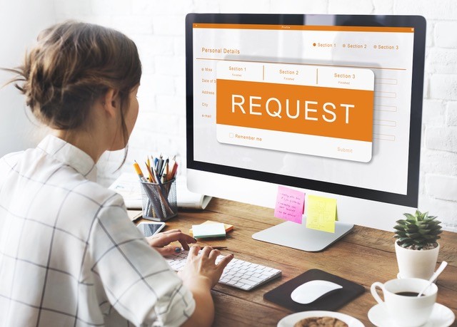 Businesswoman using computer with request message on screen.