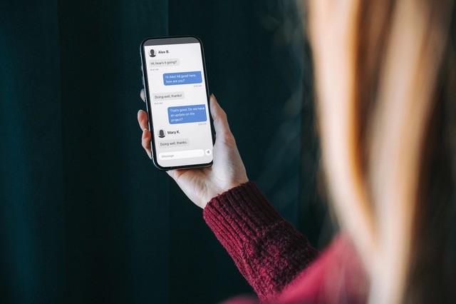 Close up of woman holding a smartphone displaying a text message.