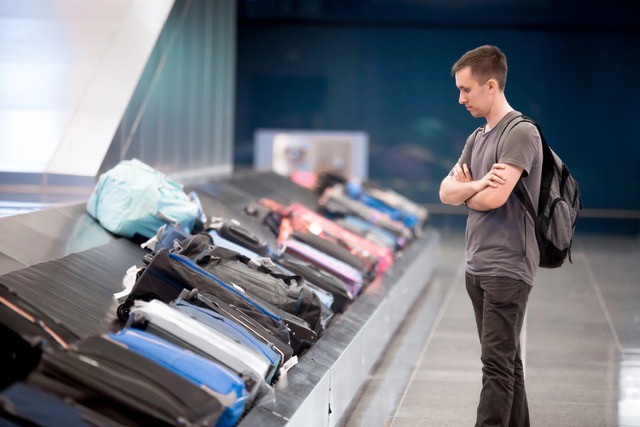 Man looking at baggage carousel at airport.