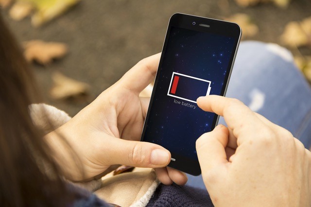 Female hands using smartphone with low battery.