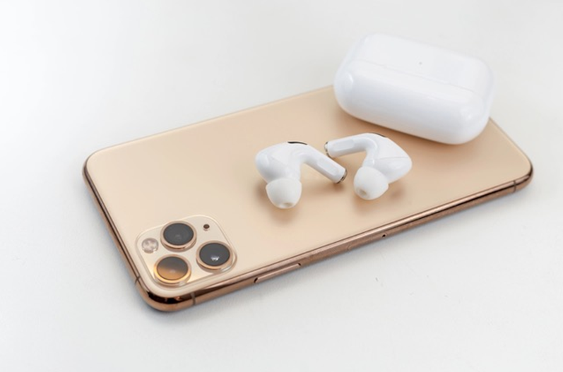 White wireless headphones next to a smart phone.