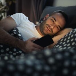 man controlling devices in bed