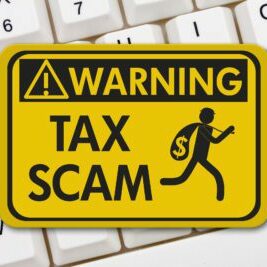 Tax scam warning sign, A yellow warning sign with text Tax Scam and theft icon on a keyboard