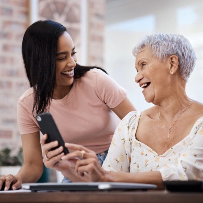 Young woman helping her elderly mother with a smart phone.