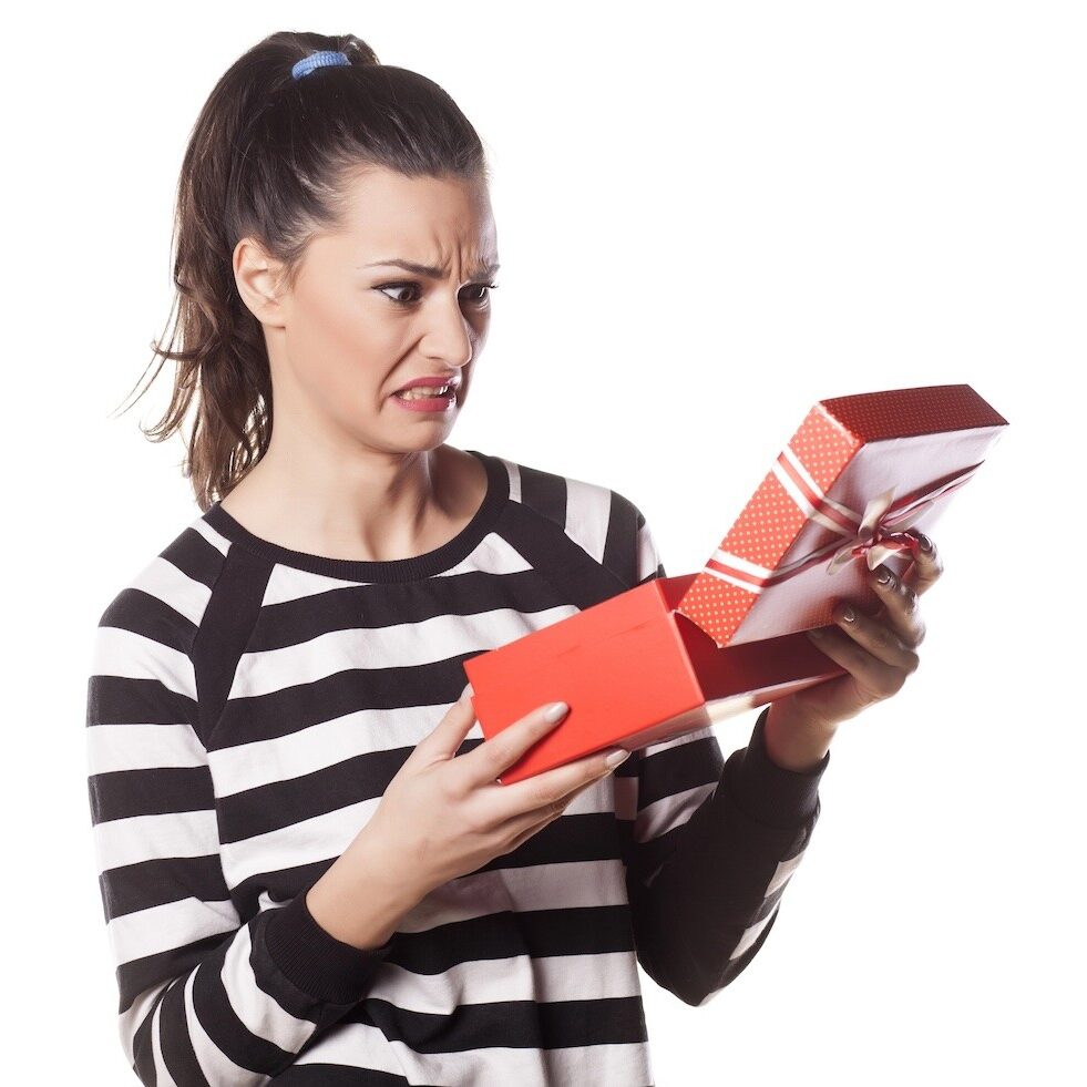 Disappointed woman holding a gift in her hands.