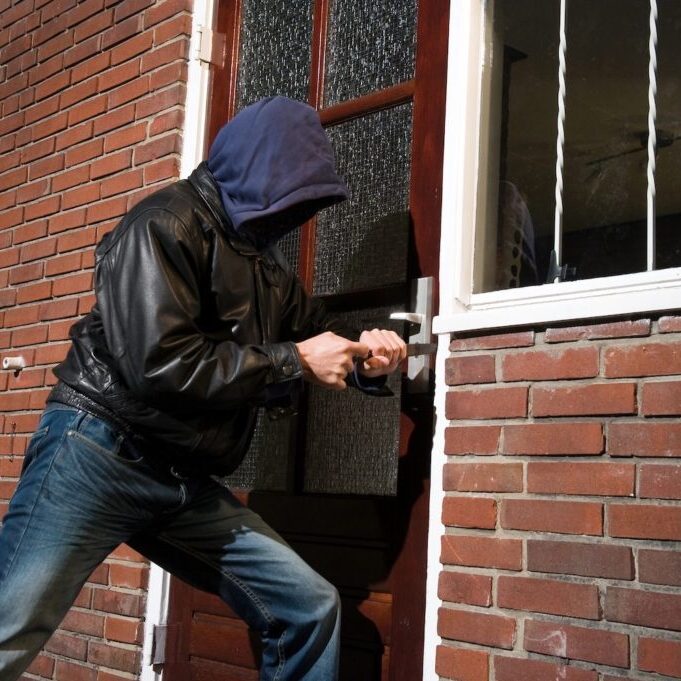 A burglar trying to get in a house through the back door.