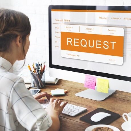 Businesswoman using computer with request message on screen.