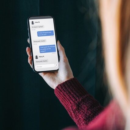 Close up of woman holding a smartphone displaying a text message.