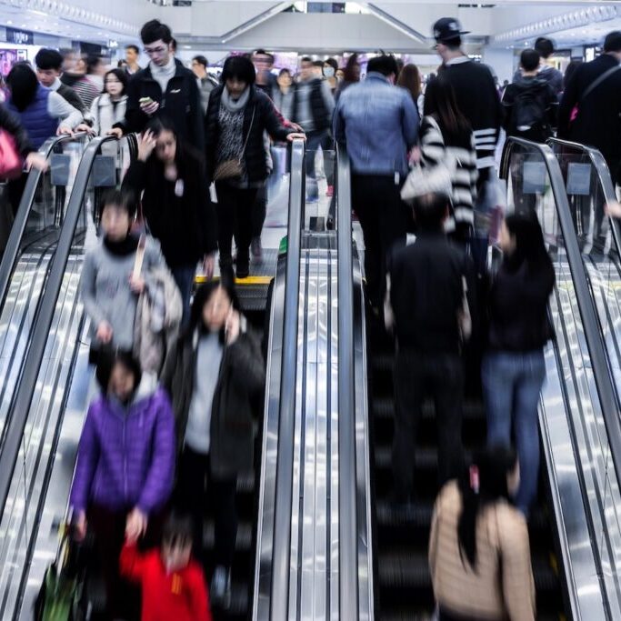 People going up and down an escalator at a shopping mall.