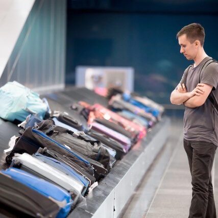 Man looking at baggage carousel at airport.