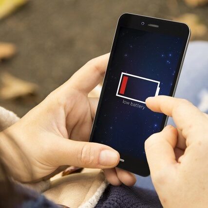 Female hands using smartphone with low battery.