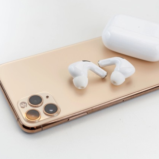 White wireless headphones next to a smart phone.