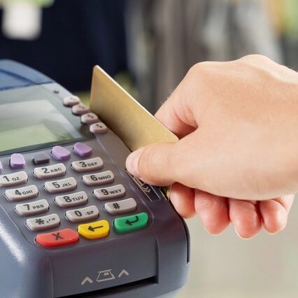 Close up of a payment machine with a hand nearby with credit card.