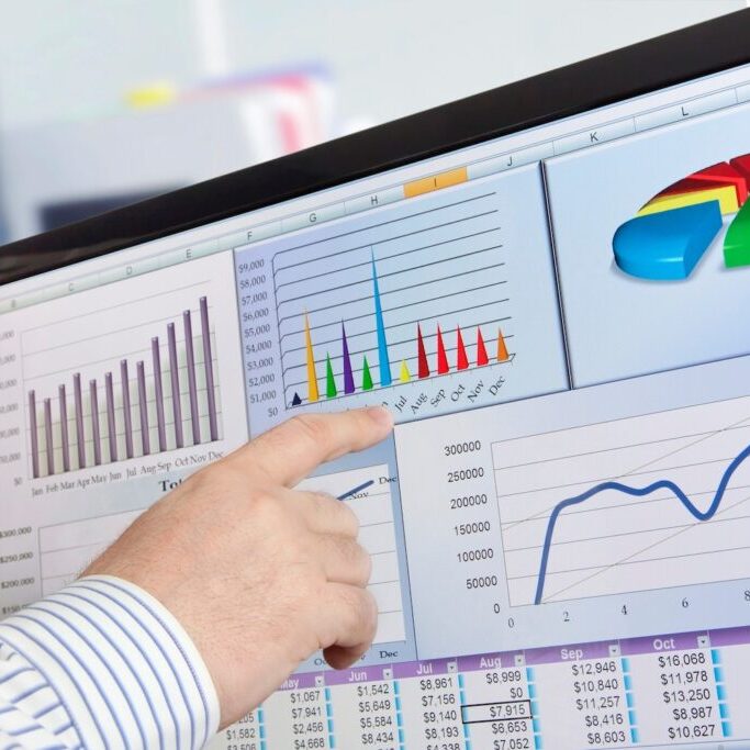 Man analyzing data and charts on a computer screen.